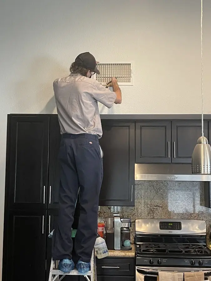 Technician inspecting an air vent during HVAC service in Manhattan